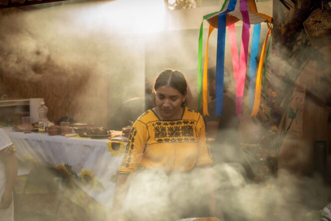 Mujer prepara alimentos tradicionales entre humo durante una actividad cultural en Michoacán